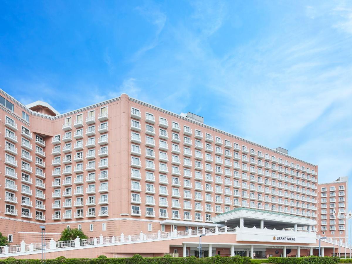 Grand Nikko Tokyo Bay Maihama Hotell Urayasu Exteriör bild The photo depicts a large hotel building featuring a contemporary architectural design. The structure is predominantly pink, with multiple floors and numerous windows. There is a covered entrance at the front, and the setting appears to be well-maint