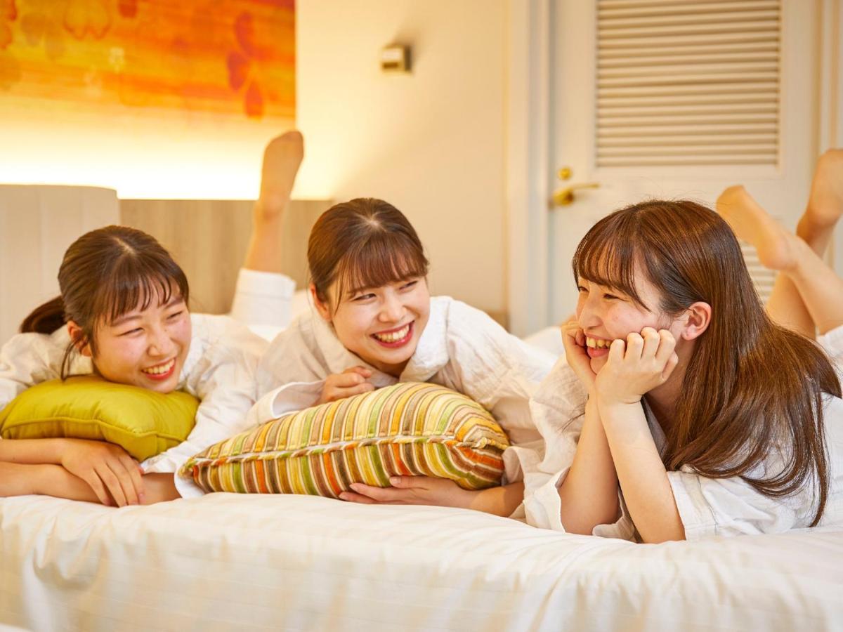 Grand Nikko Tokyo Bay Maihama Hotell Urayasu Exteriör bild The photo shows three young women lounging together in a cozy indoor setting. They are dressed in white robes and appear to be relaxed and enjoying each other's company. The women are lying on a bed, with two of them resting on their arms and the thi