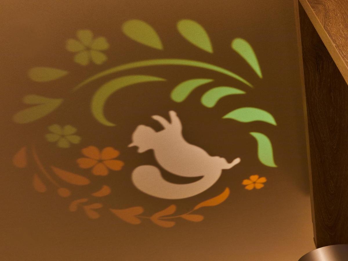 Grand Nikko Tokyo Bay Maihama Hotell Urayasu Exteriör bild The photo shows a colorful projection on a surface that includes a playful illustration. The design features a white silhouette of a squirrel in a lively pose, surrounded by decorative elements like green leaves and flowers in shades of orange and ye