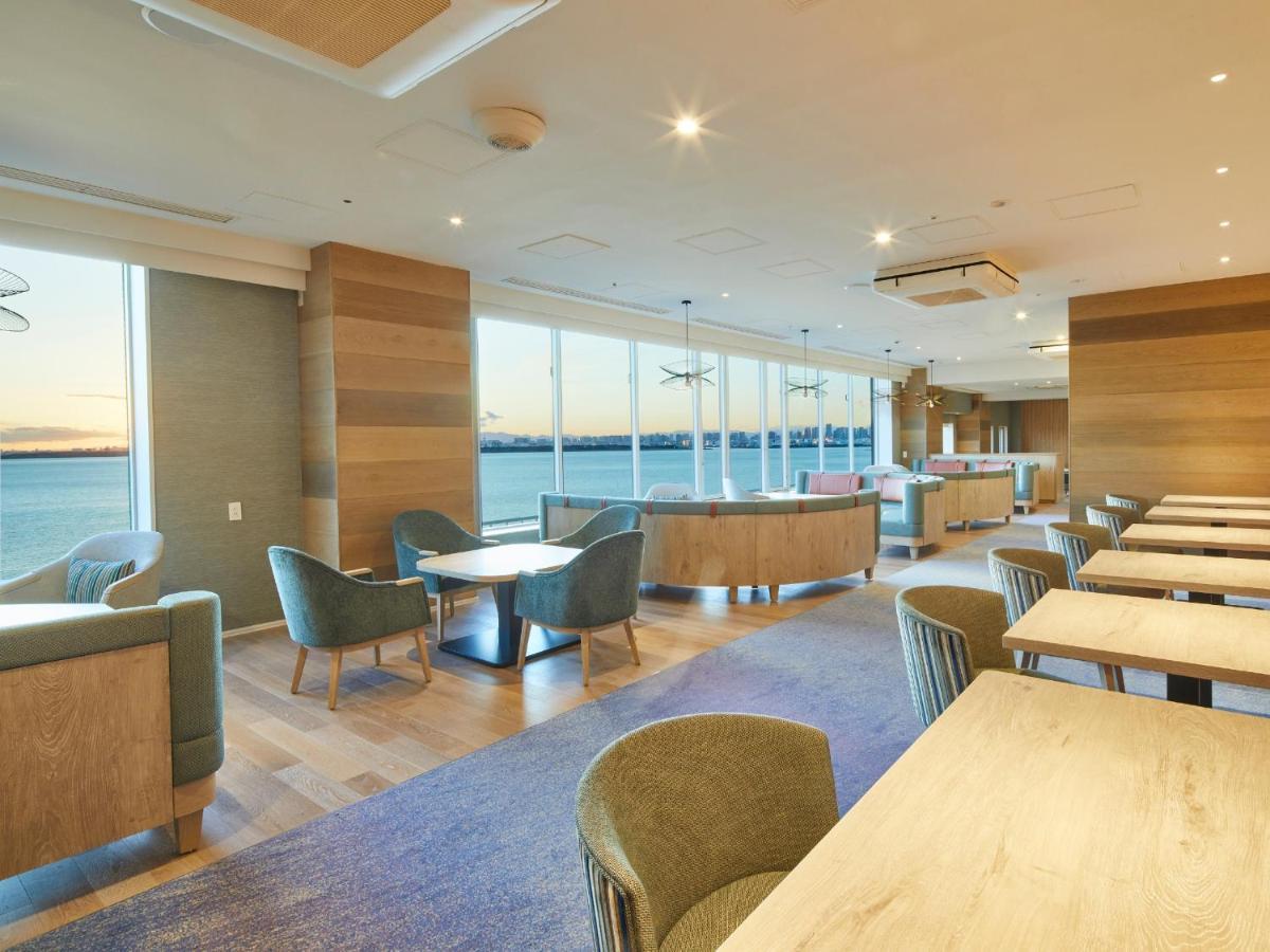 Grand Nikko Tokyo Bay Maihama Hotell Urayasu Exteriör bild The photo shows a modern interior space, likely a dining or lounge area. It features large windows that offer a view of the water, allowing natural light to fill the room. The decor includes wooden walls and stylish, comfortable furniture, with sever