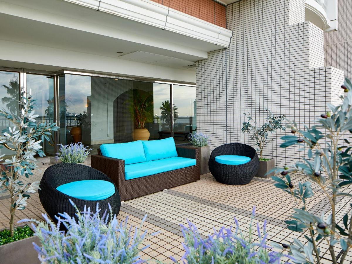 Grand Nikko Tokyo Bay Maihama Hotell Urayasu Exteriör bild The image shows a stylish outdoor seating area. There is a brown couch with turquoise cushions, complemented by two matching round chairs nearby. The seating is arranged on a tiled patio, which is bordered by planters featuring lavender flowers and g