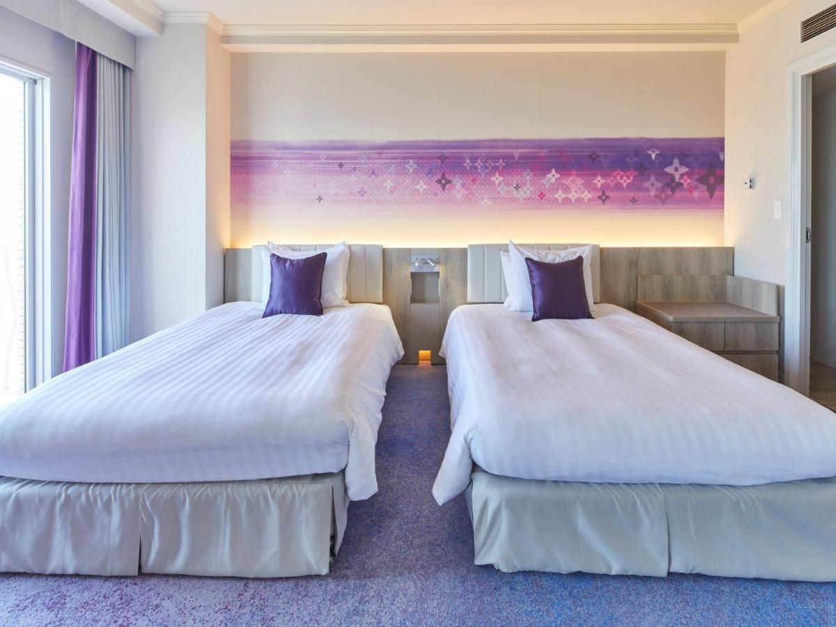 Grand Nikko Tokyo Bay Maihama Hotell Urayasu Exteriör bild The photo shows a hotel room featuring two twin beds with white bedding and purple accent pillows. The beds are positioned next to each other, with a light-colored headboard. Behind the beds, there is a decorative wall with a gradient of purple hues.